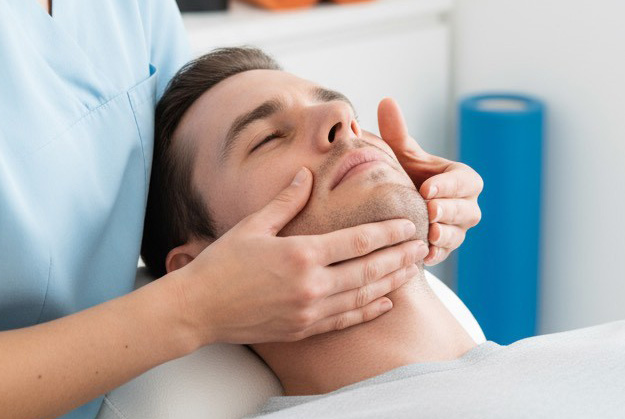 Therapeut behandelt Gesicht und Kieferbereich